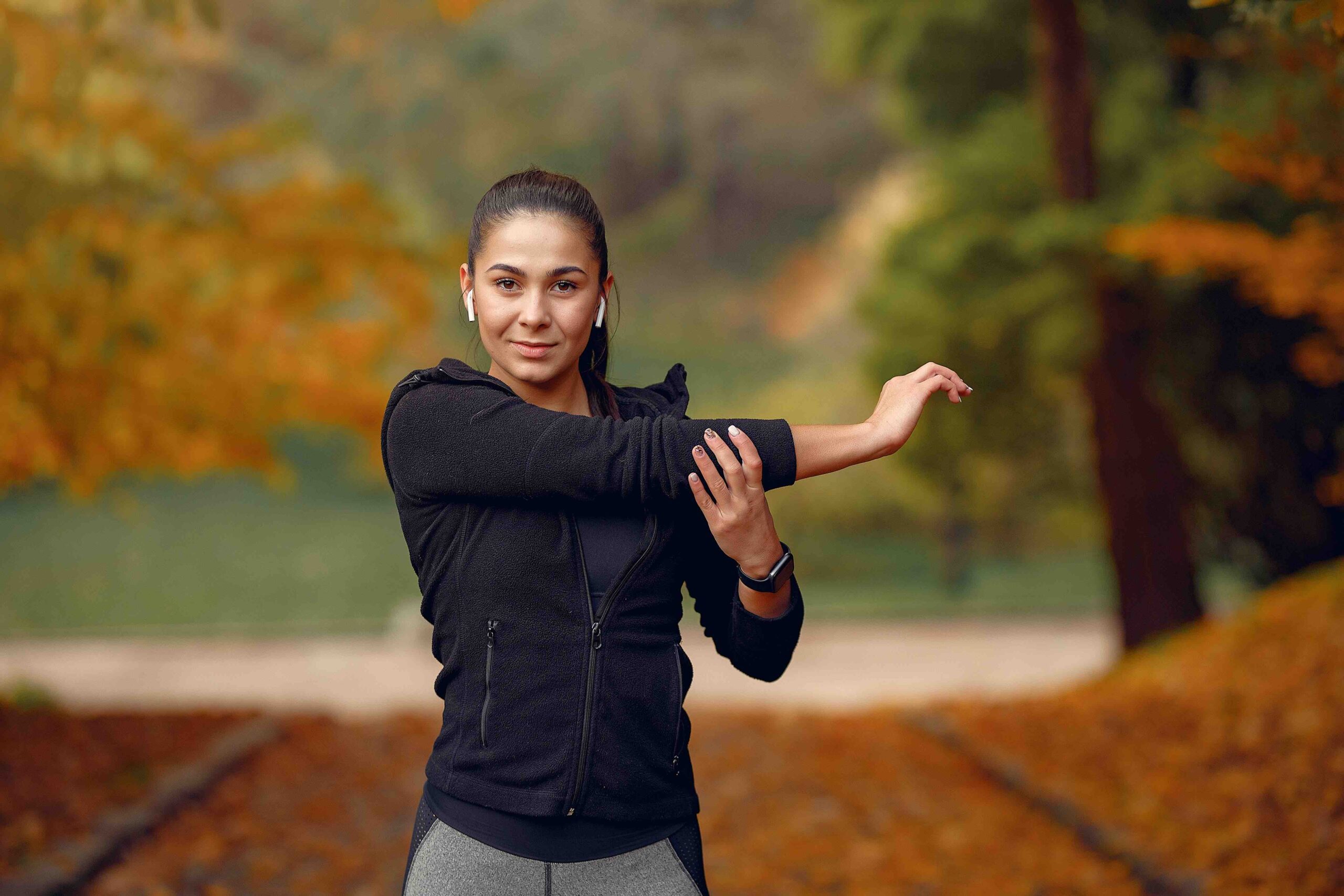 Weight Loss Journey. A girl wearing sports wear black top and gray leggings in the park amongst autumn trees