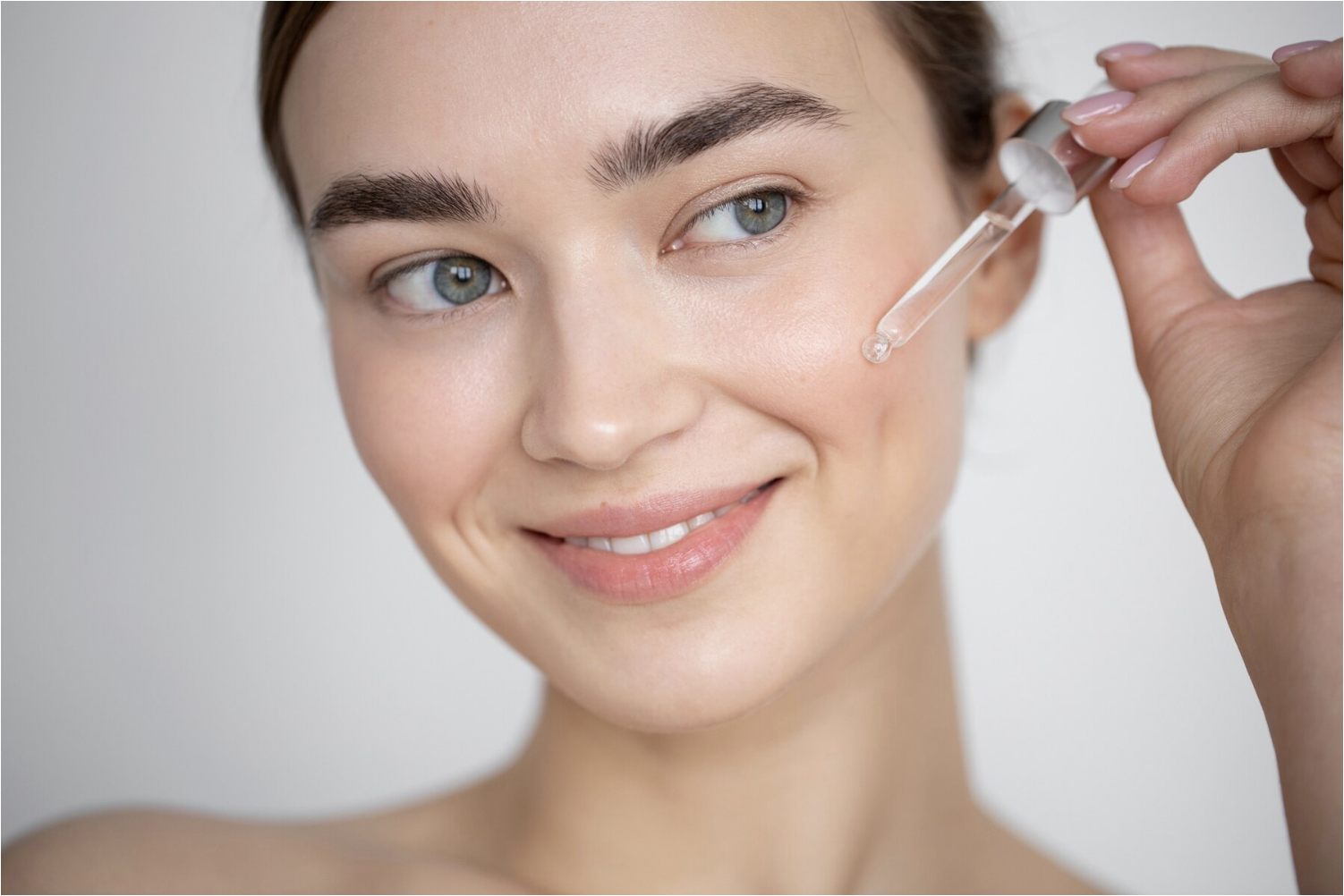 A youthful looking woman using a dropper to put Peptides for skin